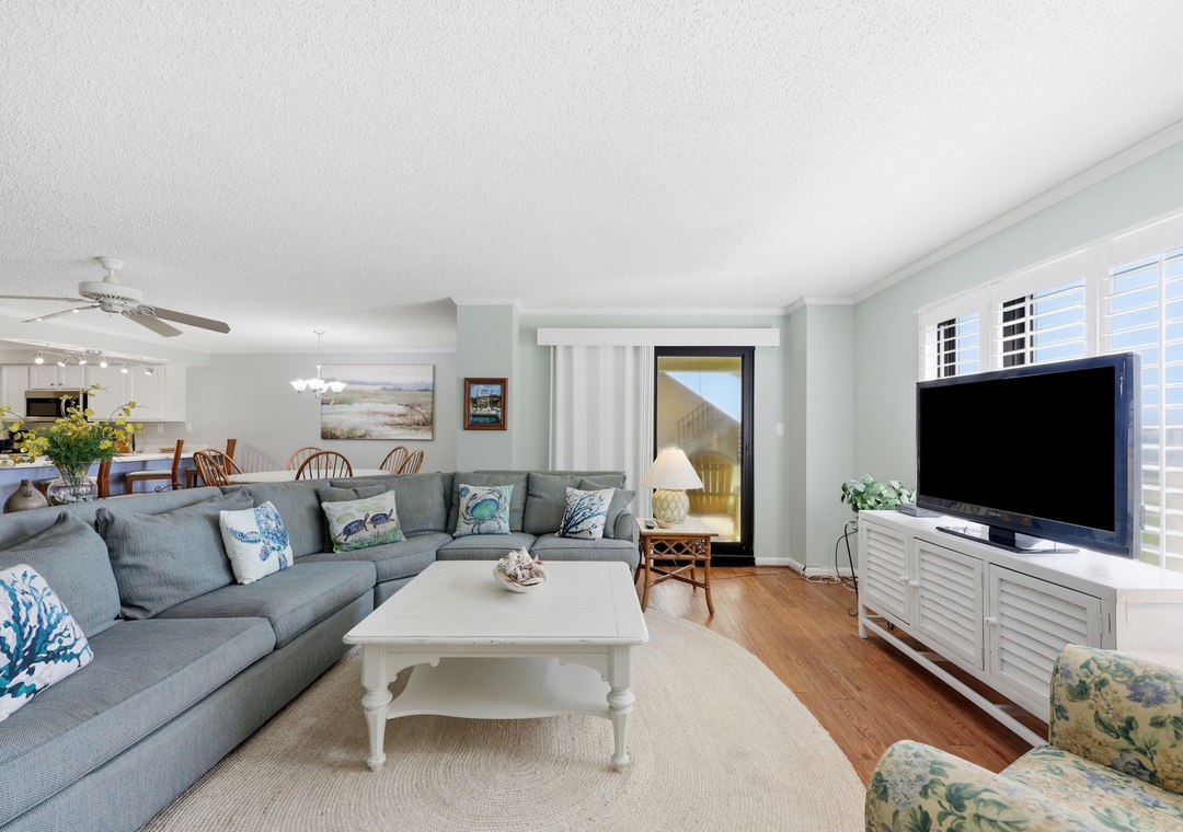 Settle into this airy coastal living room where soft blues and whites create your perfect beach retreat. Relax on the spacious sectional as natural light fills your open-concept space.