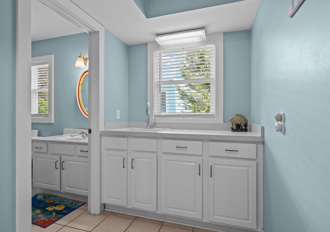 Refresh in your bright, coastal-themed bathroom featuring sleek white cabinetry and calming blue walls that create a serene spa-like atmosphere.