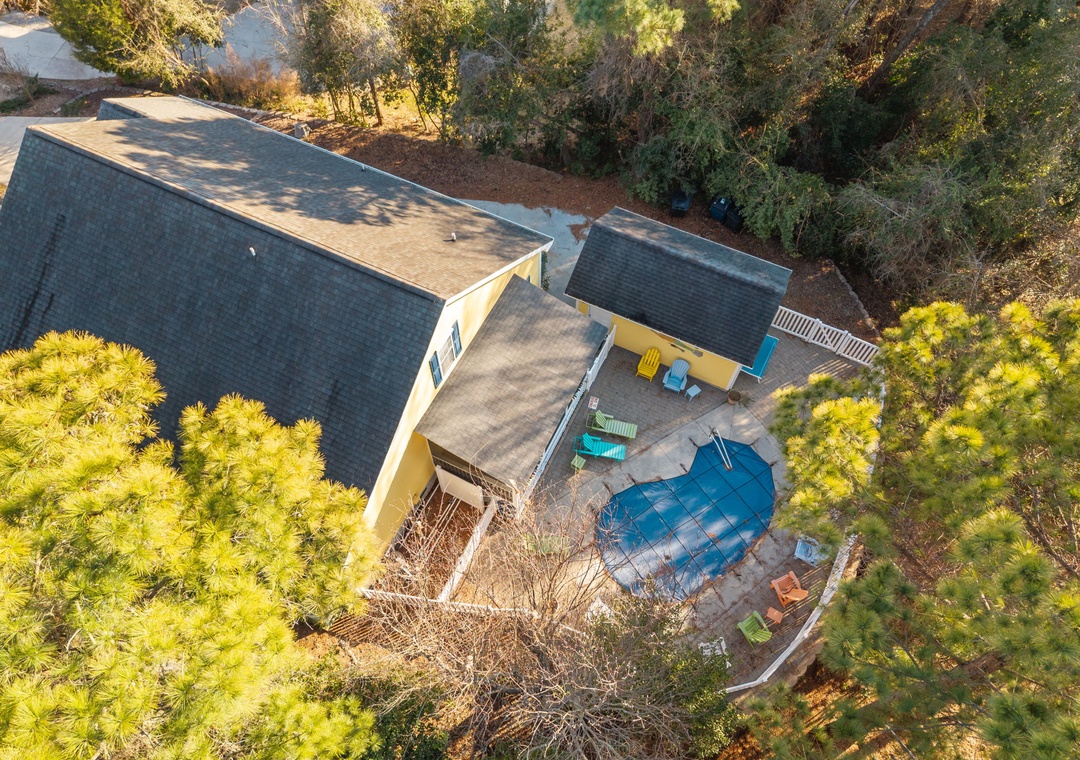 Aerial view of the property showcasing the main building, swimming pool, and lush natural surroundings nestled among mature trees.