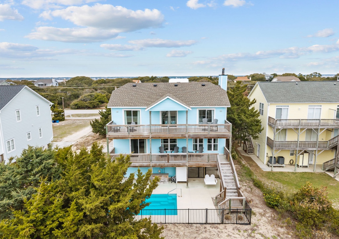 Aerial view of beachfront vacation homes nestled among coastal vegetation, with swimming pools and easy beach access in this scenic waterfront community.
