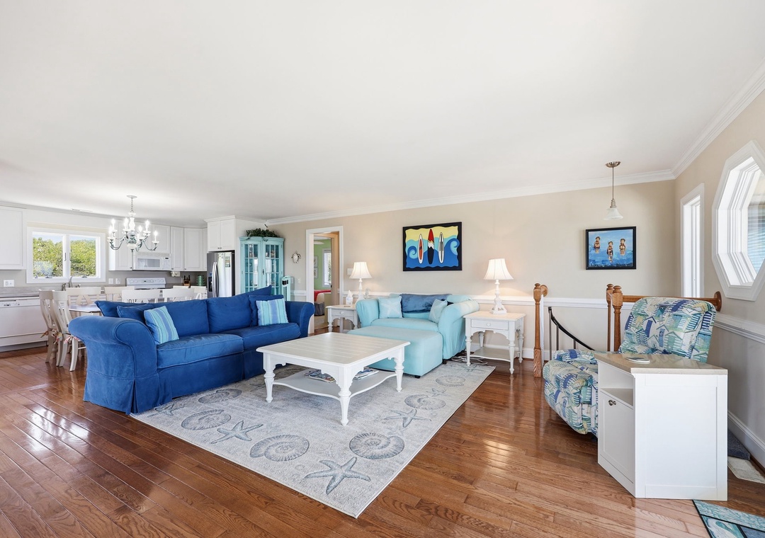 Sink into plush coastal sofas where natural light streams through windows. The open-concept design connects you to the dining and kitchen areas, perfect for gathering with loved ones.