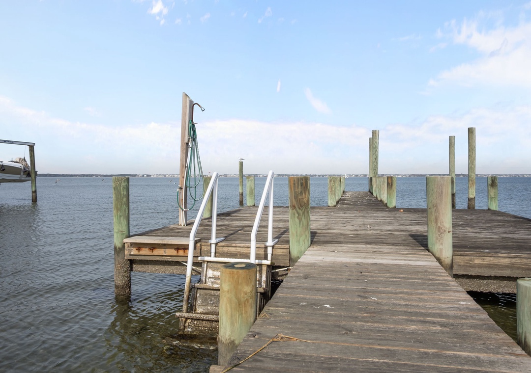 Private waterfront dock extends into calm bay waters, offering direct access for boating adventures and peaceful moments by the water.