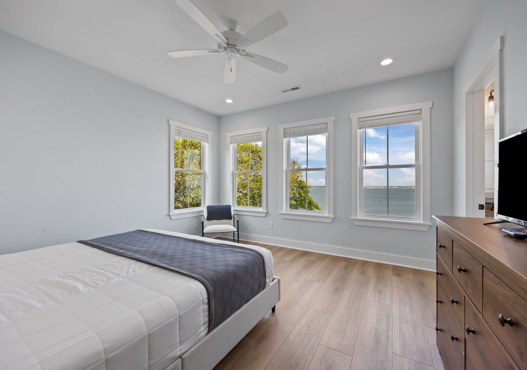 Your serene bedroom sanctuary with stunning water views through bay windows. Ceiling fan keeps you comfortable while watching boats drift by.
