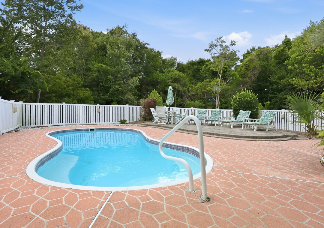 Private freeform pool surrounded by patterned terracotta pavers, lush greenery, and inviting lounge chairs—your perfect spot to soak up the sun and unwind.