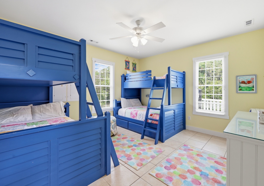 Your kids will love this cheerful room with vibrant blue bunk beds and sunny yellow walls. Soft rugs underfoot and a ceiling fan overhead make their space cozy and comfortable.