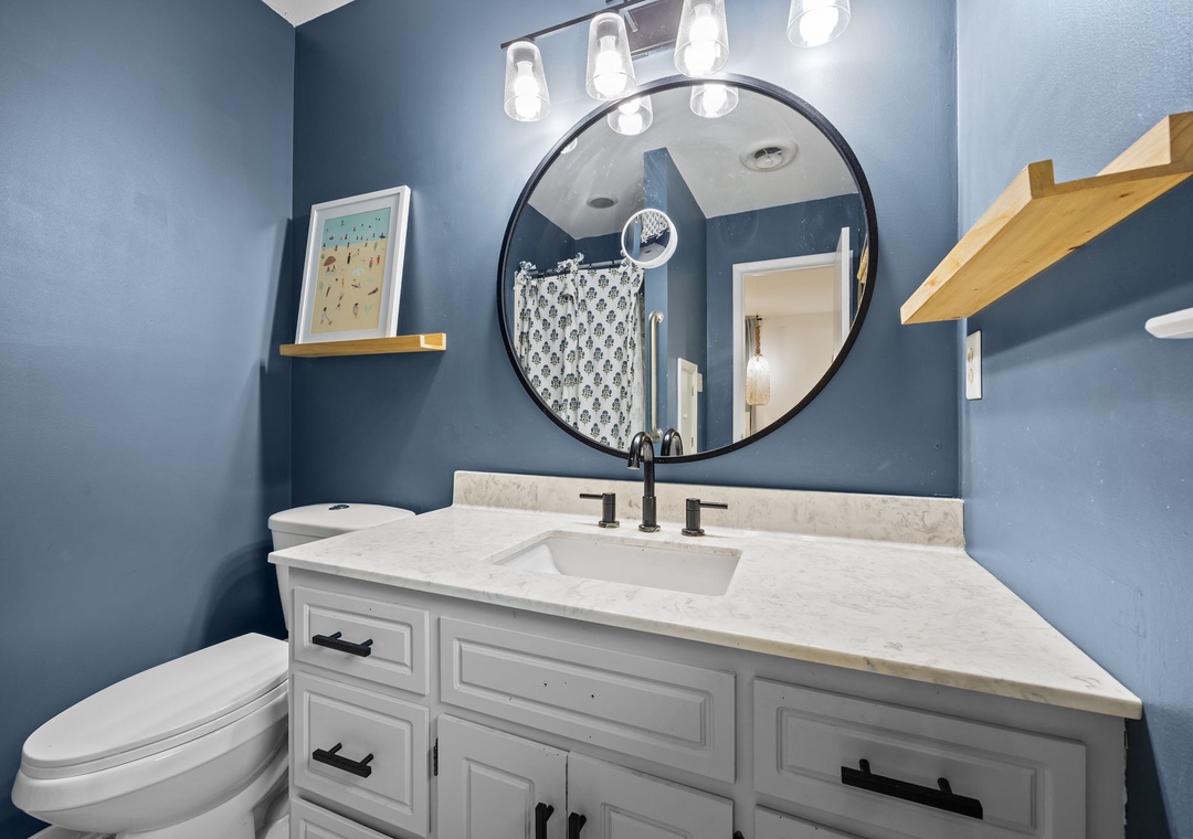 Your stylish powder room features elegant blue walls, marble countertops, and thoughtful touches that make freshening up a luxurious experience.