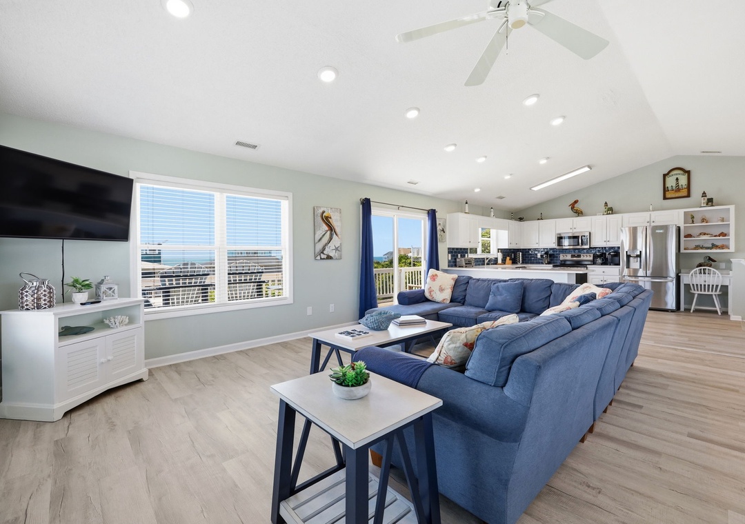 Unwind on plush blue sofas in this bright, open-concept living space with coastal views. The spacious layout flows into a fully-equipped kitchen, perfect for gathering after a day at the beach.