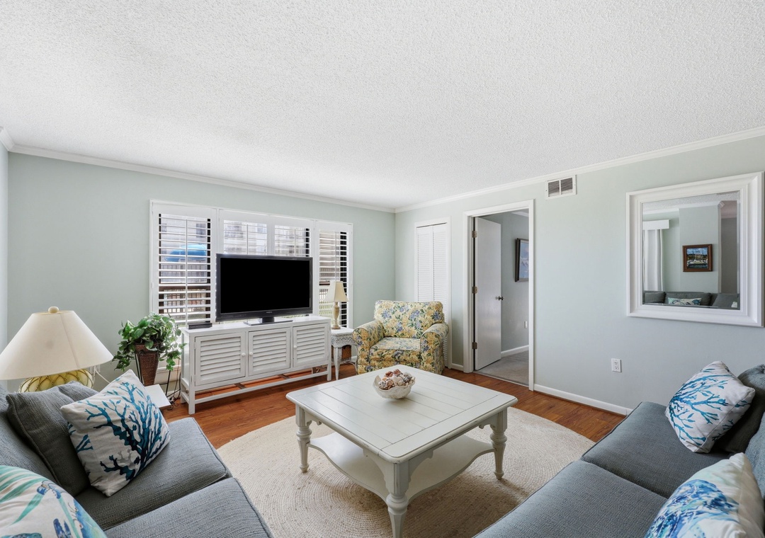 Relax in your bright, coastal-inspired living room with plush seating, hardwood floors, and cheerful décor—perfect for unwinding after a day at the beach.