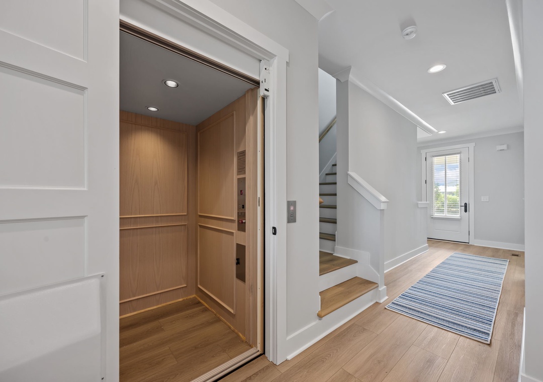 Step into your bright, modern entryway featuring warm hardwood floors, elegant white trim, and convenient elevator access for effortless movement.