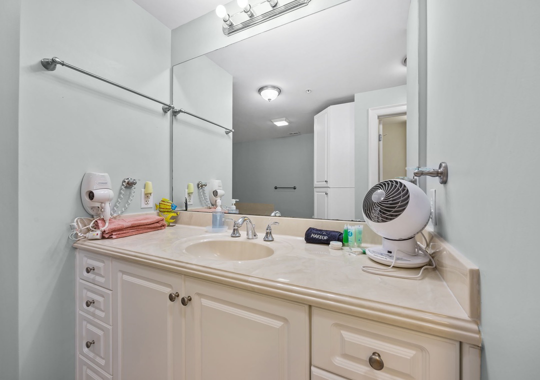 Enjoy your spacious bathroom with modern vanity, ample storage, and thoughtful amenities including hair dryer for your convenience.
