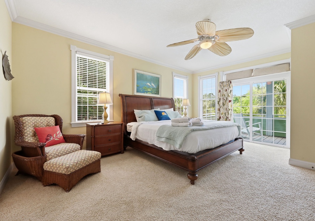 Unwind in your spacious bedroom with coastal charm, a plush king bed, cozy seating, and sliding doors opening to your private balcony with lush tropical views.