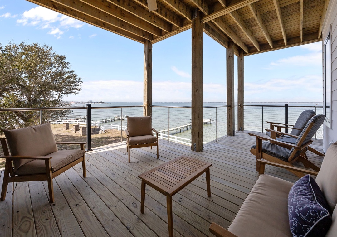 Waterfront deck with comfortable seating overlooking peaceful waters and scenic docks - your perfect spot to unwind.