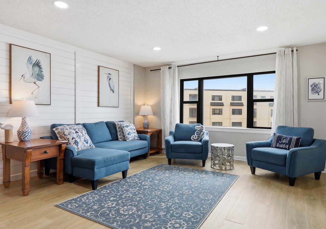 Unwind in your serene living space, where coastal blues and natural textures create the perfect backdrop for your relaxing getaway. Light floods through large windows, inviting you to settle in.