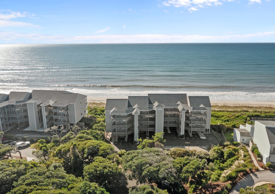 Oceanfront resort buildings nestled among lush coastal vegetation with direct beach access and pristine shoreline views.