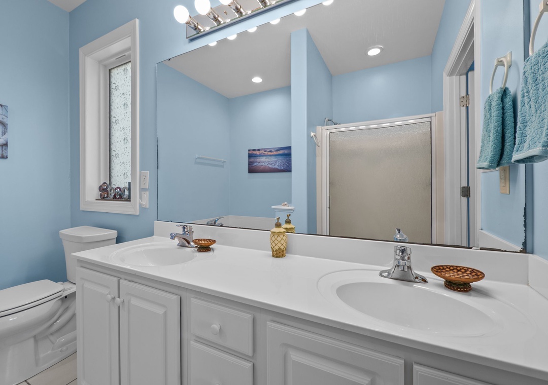 Step into your serene bathroom oasis with calming blue walls, dual vanity, and warm lighting that makes your morning routine feel luxurious.