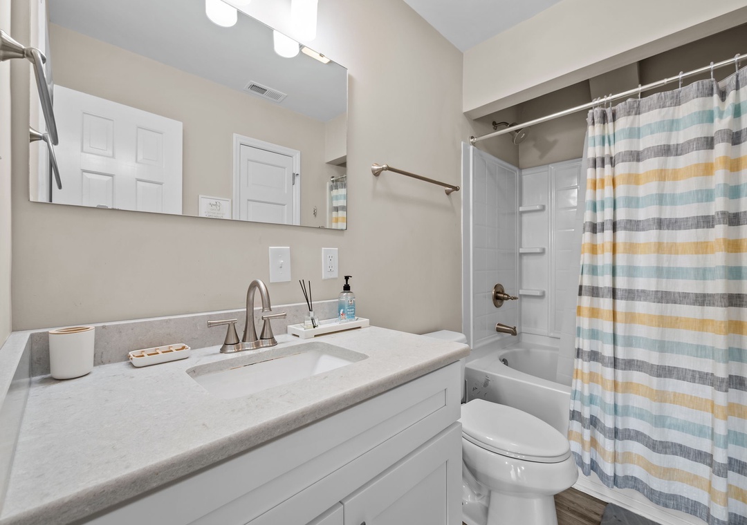 Refresh in your bright, modern bathroom with pristine finishes, soft lighting, and cheerful striped accents.