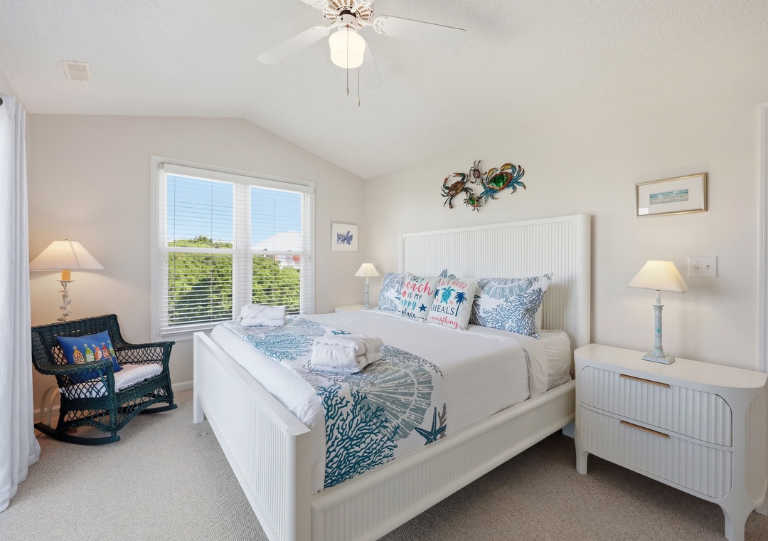 Sink into crisp white linens and ocean-inspired accents in your light-filled bedroom, where coastal charm meets comfort and every morning starts with natural light streaming through your windows.