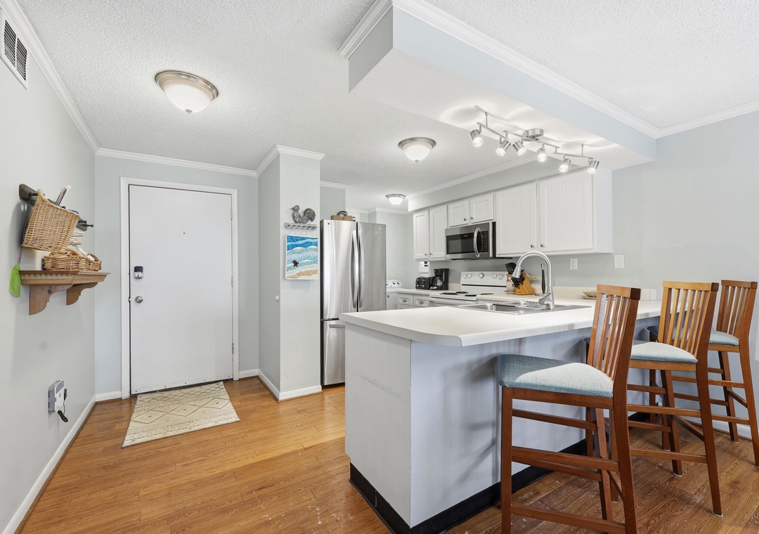 Your bright, open-concept kitchen invites you to gather around the breakfast bar, where coastal charm meets modern convenience for meals and memories.