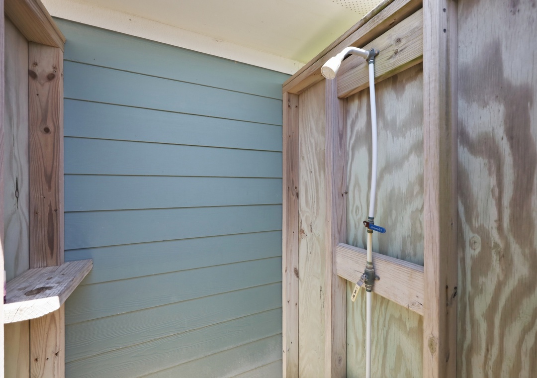 Simple outdoor shower with bench and painted shiplap wall—perfect for rinsing off sand and salt after a day at the beach.