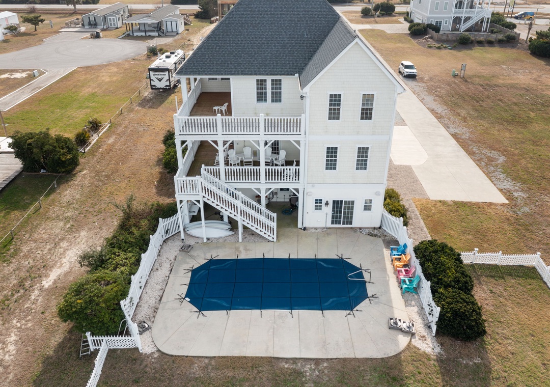 Stunning aerial view showcases this beach house retreat with private pool, multi-level decks, and spacious grounds in a peaceful residential setting.