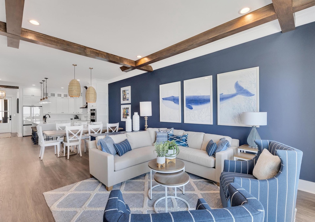 Picture yourself relaxing in this bright coastal retreat, with exposed beams overhead and nautical artwork setting the tone. The open living space flows seamlessly into the dining area and modern kitchen—perfect for your getaway.