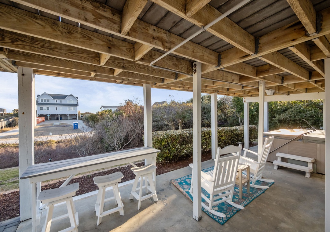 Relax in your covered outdoor living space with comfortable seating and peaceful neighborhood views beyond the landscaped garden.