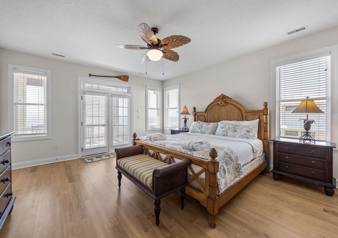 Drift off in your tropical bedroom featuring hardwood floors, bamboo-style bed, ceiling fan, and French doors opening to your private balcony.