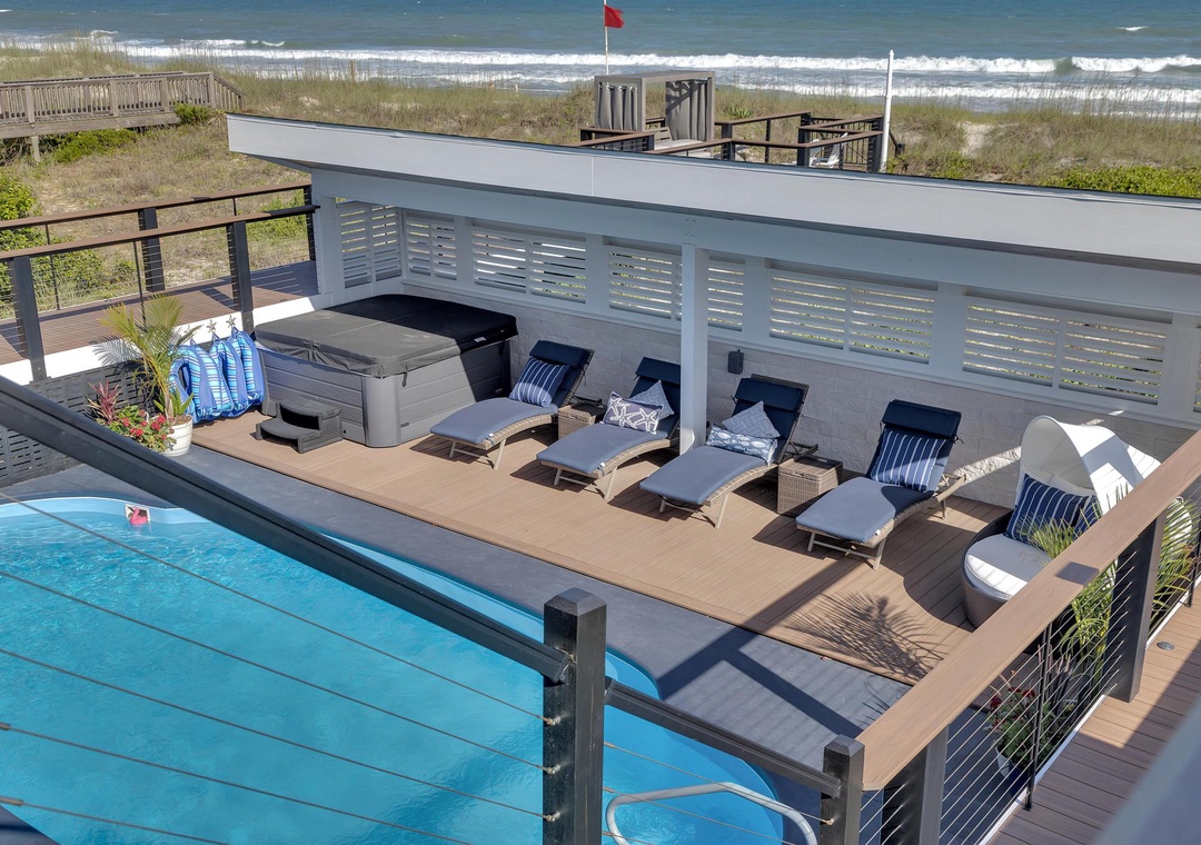 Oceanfront pool deck with steps-from-the-beach access, where you'll unwind on cushioned loungers under coastal skies and enjoy direct paths to the waves.