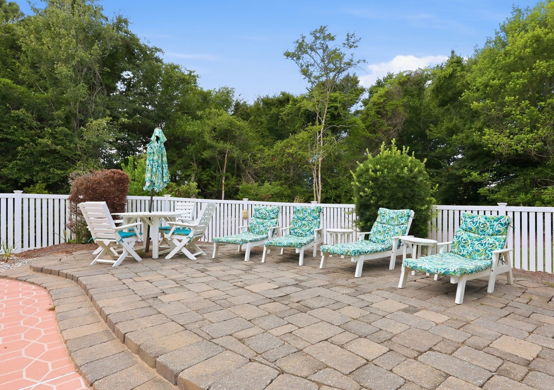 Settle into these cushioned lounge chairs on the spacious patio, where you can soak up the sun surrounded by lush greenery and enjoy peaceful outdoor moments.