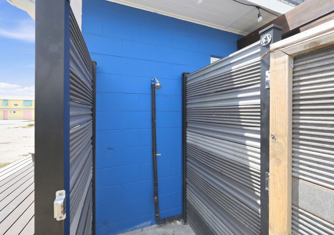 Outdoor shower with corrugated metal privacy walls, ideal for rinsing off after beach days or outdoor adventures.