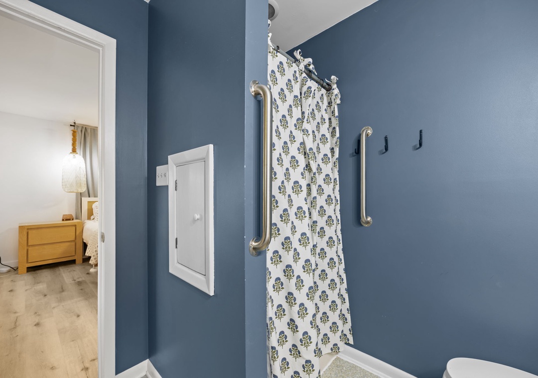 Step into your accessible bathroom with thoughtful grab bars and charming floral shower curtain for comfort and safety.