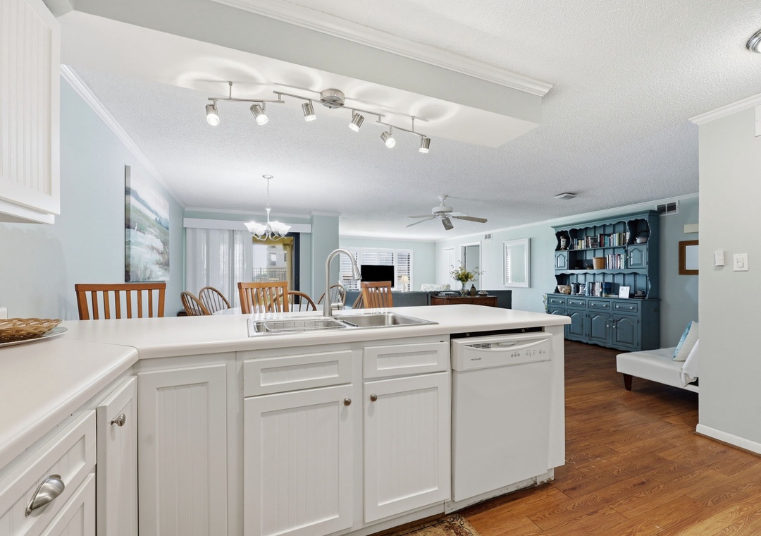 Picture yourself cooking in this bright, open kitchen with crisp white cabinetry, modern appliances, and flowing hardwood floors connecting to your dining and living spaces.