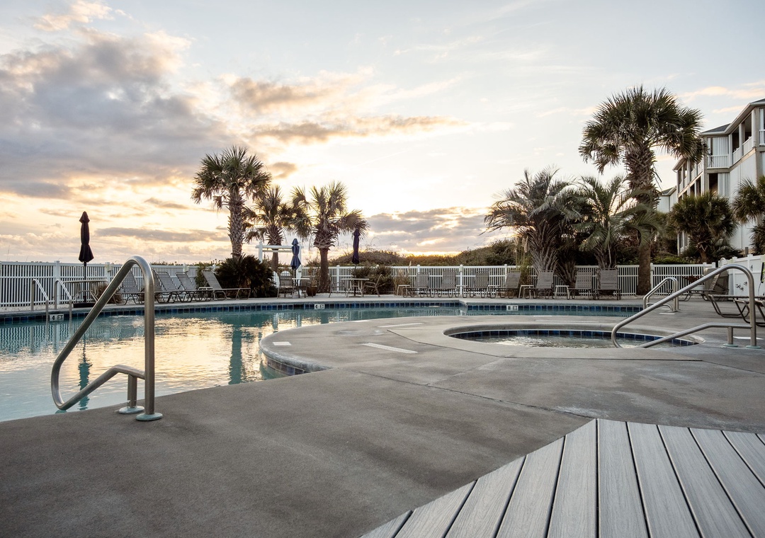 Coastal pool deck with palm trees and property buildings capturing the golden hour atmosphere of this beachfront location.