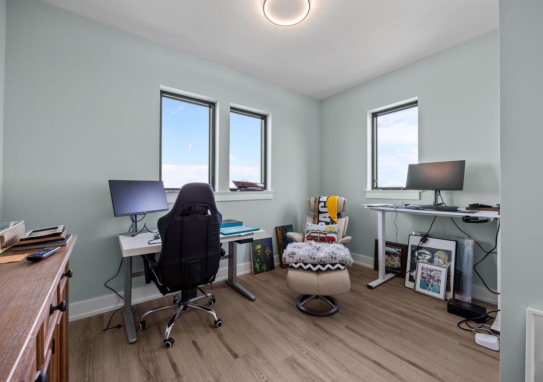 Stay productive in your dedicated workspace with dual monitor setup, ergonomic seating, and natural light streaming through multiple windows.