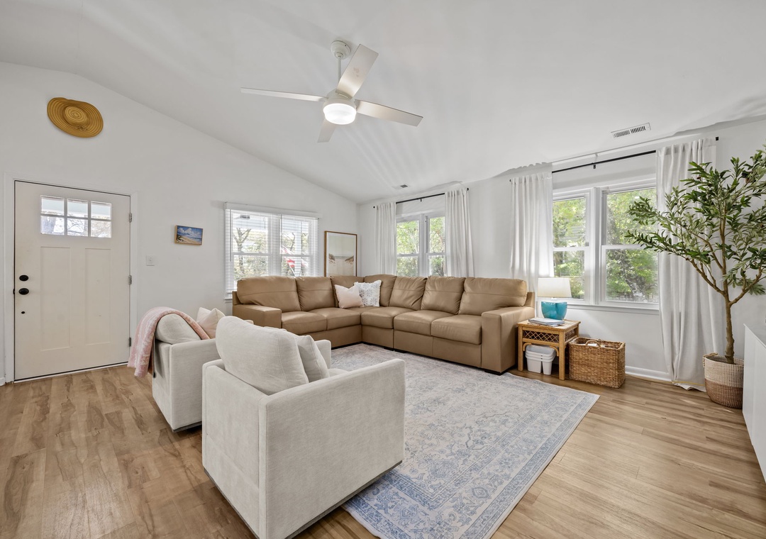 Sink into plush sectional seating in your bright living space, where natural light streams through large windows and a ceiling fan keeps you comfortable.