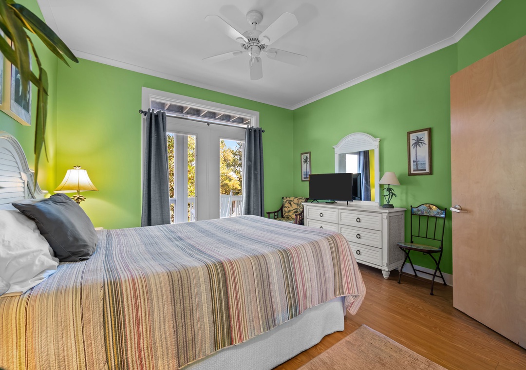 Your tropical bedroom retreat features bright green walls, ceiling fan, TV, and French doors opening to your private outdoor space.