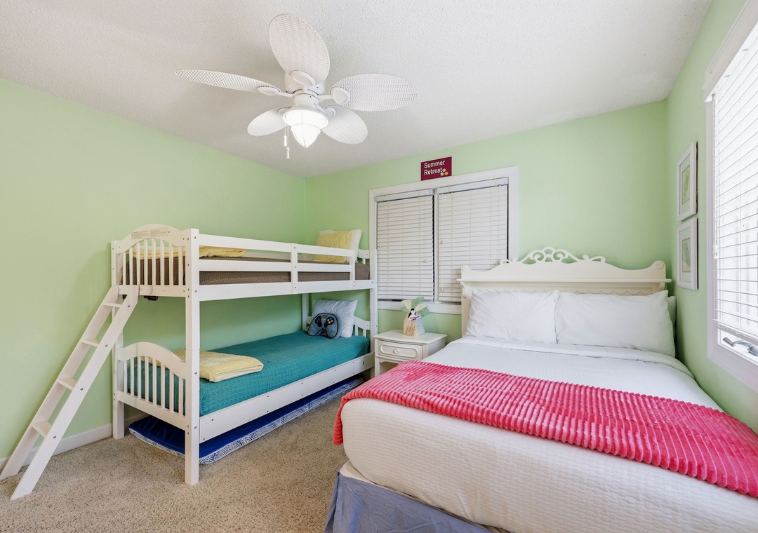 Your bright, cheerful bedroom features a cozy queen bed and a bunk bed, perfect for families. Crisp white linens, a ceiling fan, and playful pops of color create a welcoming retreat.