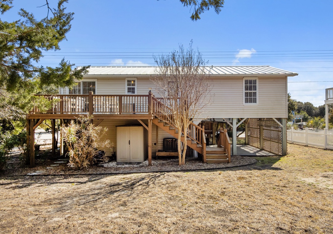 Elevated coastal retreat with wraparound deck and convenient ground-level storage in a peaceful residential setting.