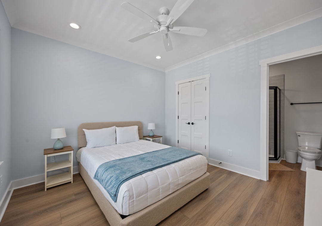 Sink into your cozy bed with soft linens and calming blue accents. The ceiling fan keeps you comfortable while ensuite convenience awaits.