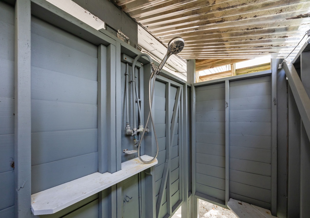 Step into your private outdoor shower sanctuary, where warm water meets cool sea breeze under rustic wooden beams.