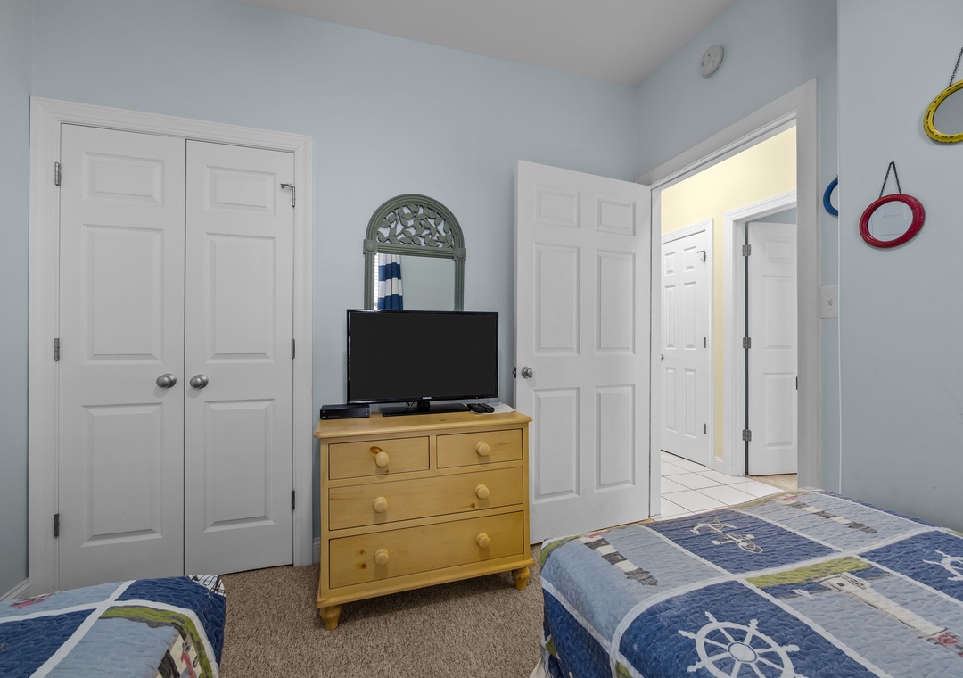 Your coastal bedroom features twin beds with charming nautical bedding and convenient entertainment setup for relaxing evenings.