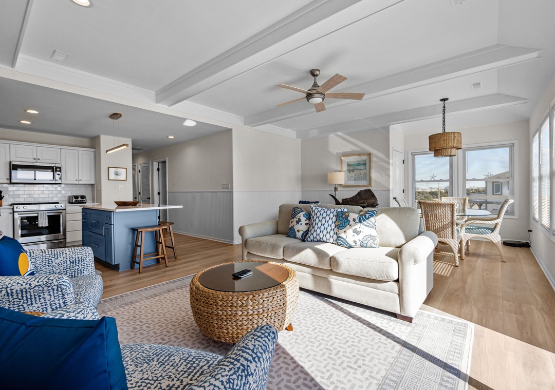 Relax in your bright, coastal-inspired living space with comfortable seating, exposed beams, and an open kitchen perfect for preparing meals together.