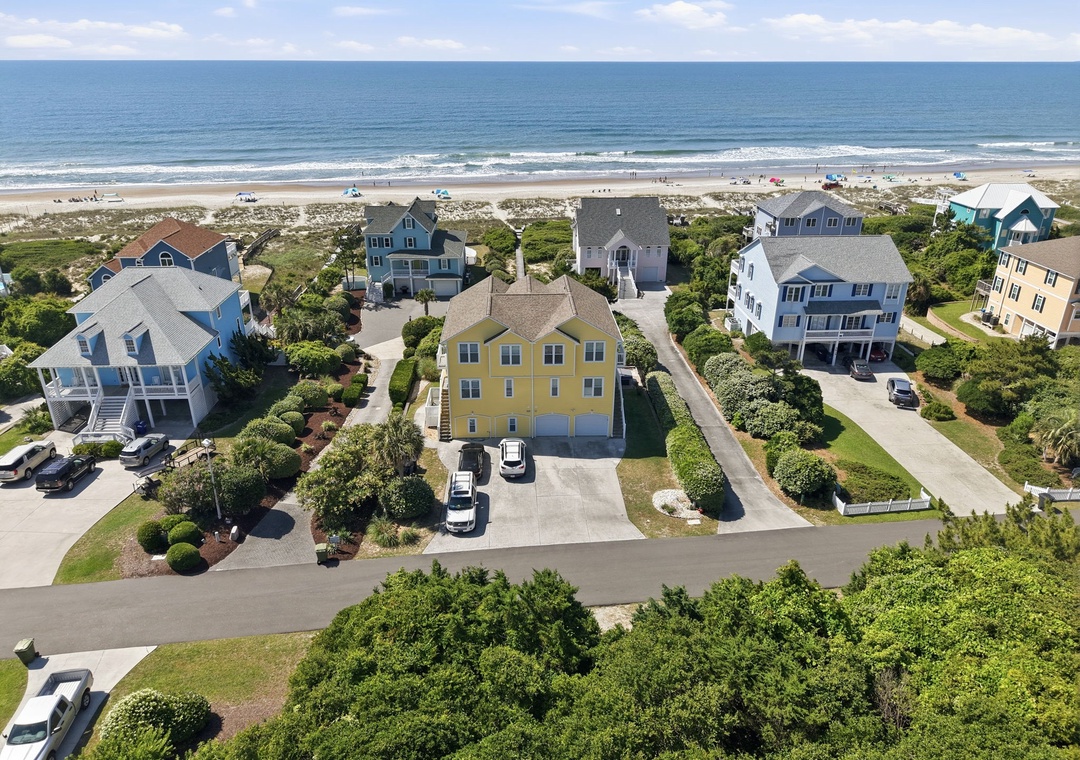 Aerial view of a coastal neighborhood featuring oceanfront vacation homes with direct beach access, landscaped grounds, and nearby sandy shores ideal for seaside getaways.