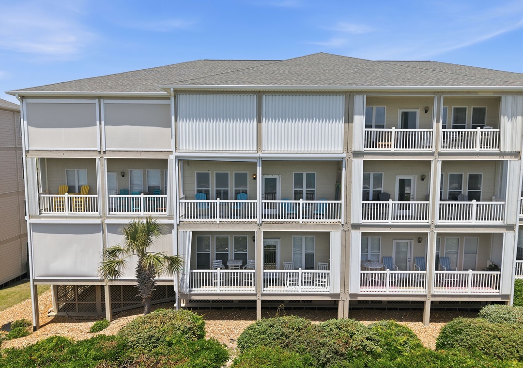 A coastal multi-level vacation property featuring spacious balconies and modern exterior design near the beach. The building showcases clean lines with contemporary coastal architecture and thoughtful landscaping.