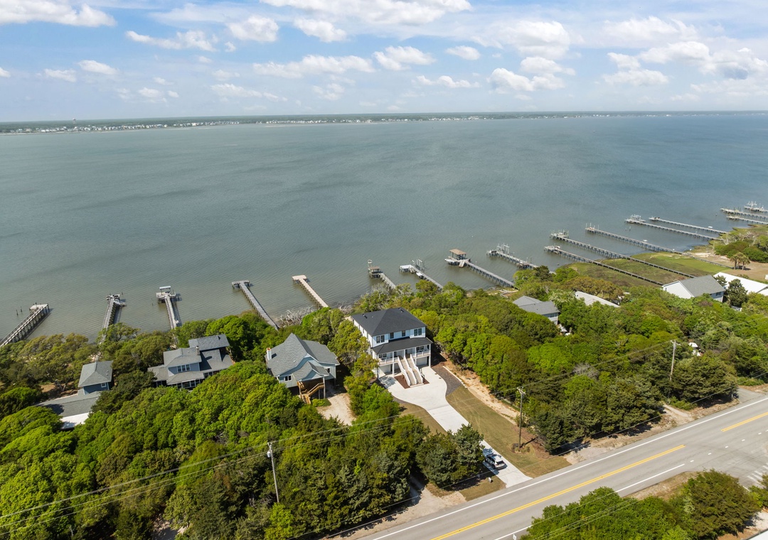 Aerial view of waterfront properties nestled among mature trees with private boat docks extending into the expansive bay waters.