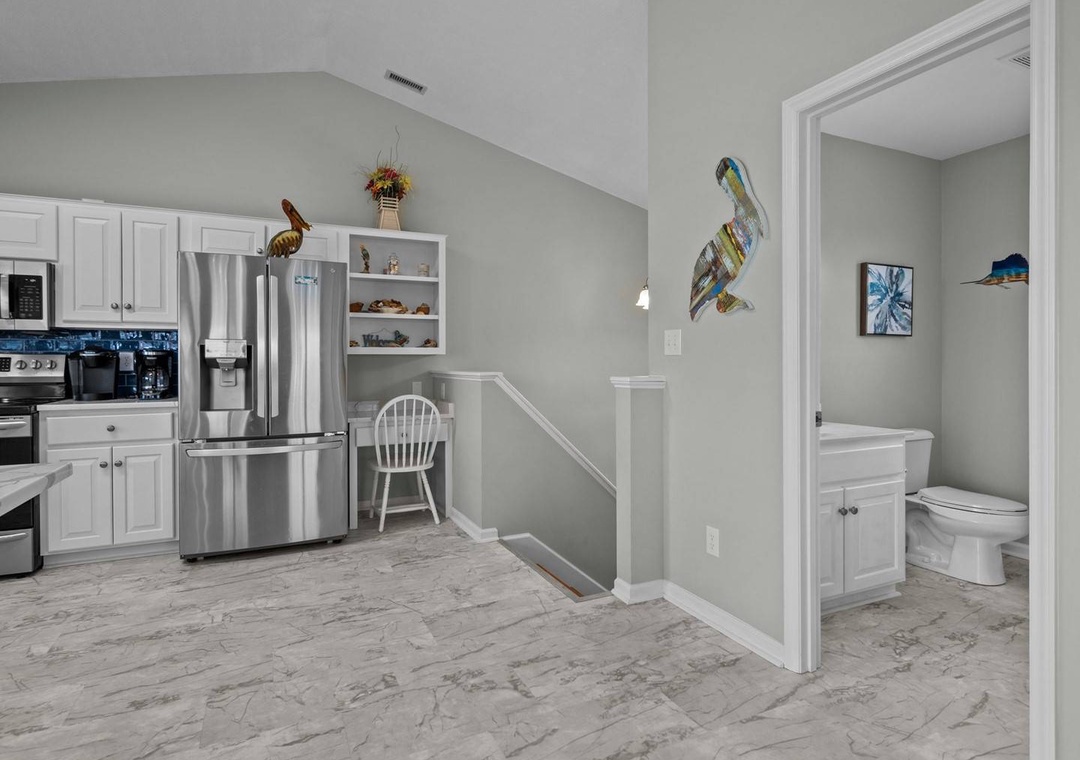 Your fully equipped kitchen flows seamlessly into a convenient powder room, offering modern stainless appliances and coastal charm.