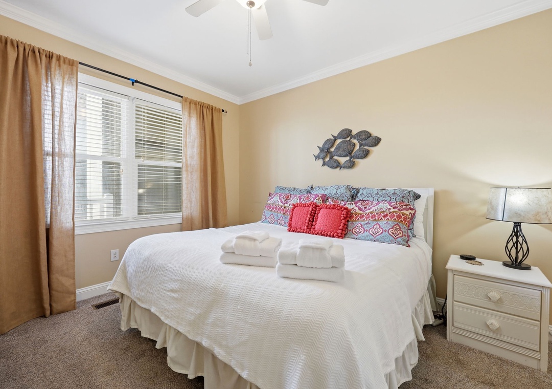 Sink into the soft bedding after a day of exploring, with natural light, a ceiling fan, and coastal décor creating your perfect retreat.