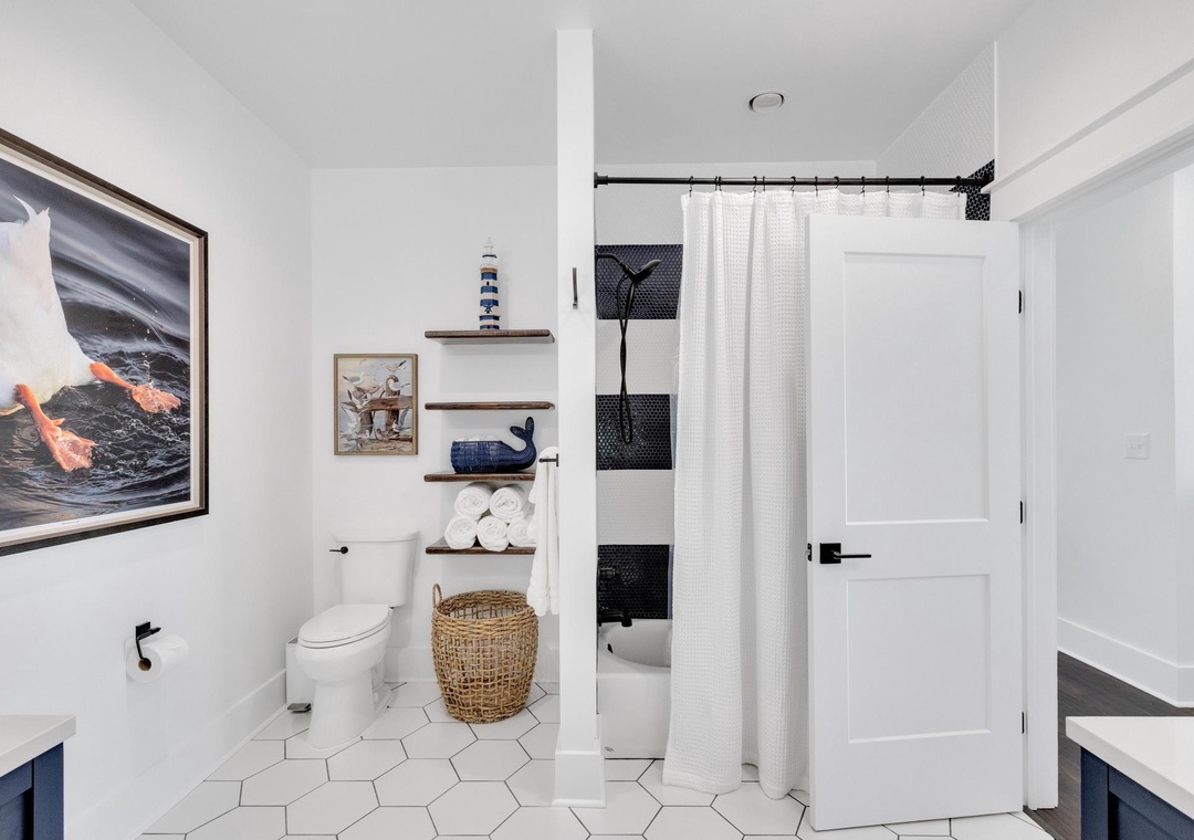 Crisp white tiles and nautical touches create a bright, refreshing retreat. Notice the thoughtful storage and classic style that make your stay effortless.