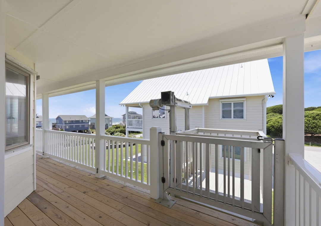 Covered deck with white railing offers a breezy outdoor retreat, perfect for morning coffee or evening relaxation while taking in the coastal neighborhood views.