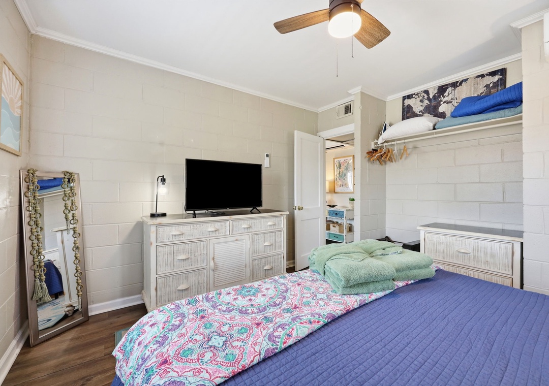 Unwind in your serene bedroom with coastal charm, featuring a plush bed, modern TV, and breezy ceiling fan to keep you comfortable during your stay.